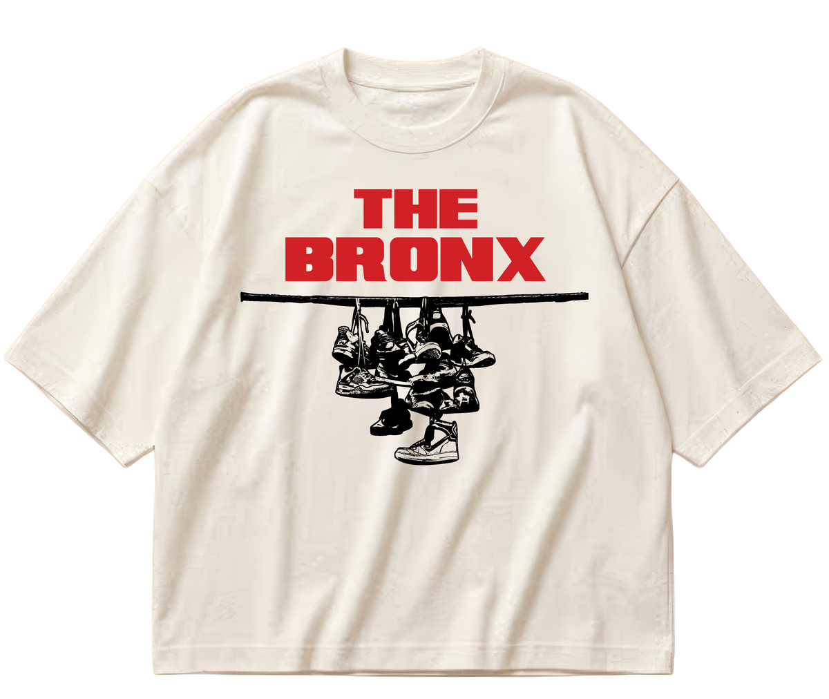 Off-white boxy cropped Sneaker Hang tee with red The Bronx lettering above a black hanging-sneakers design.