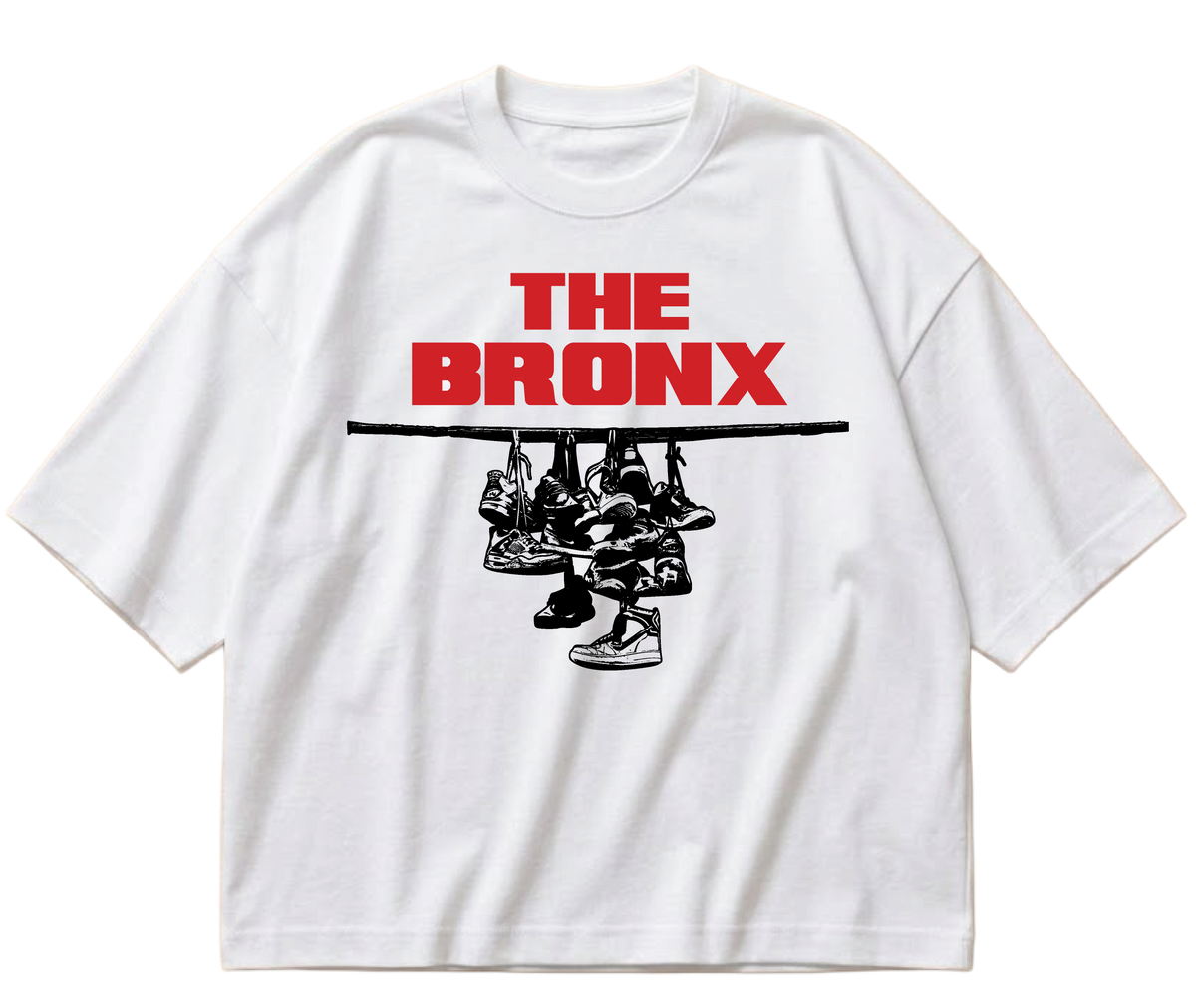 White boxy cropped Sneaker Hang tee with red The Bronx lettering above a black hanging-sneakers design.