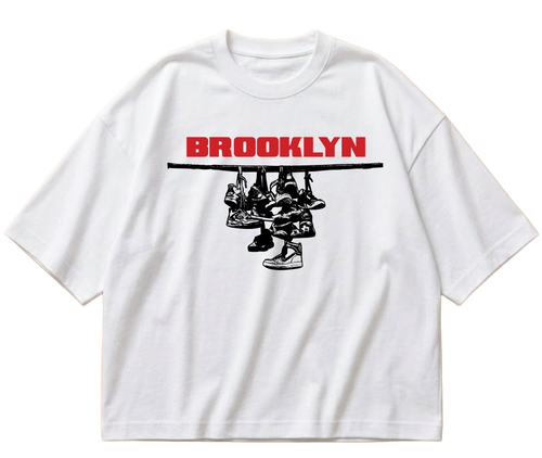 White boxy cropped Sneaker Hang tee with red Brooklyn lettering above a black hanging-sneakers design.