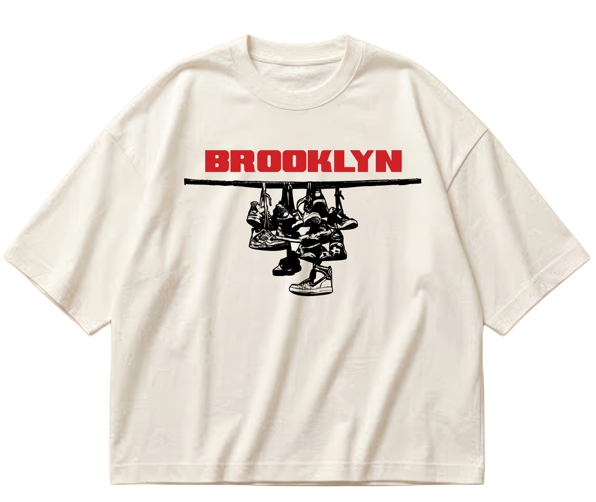 Off-white boxy cropped Sneaker Hang tee with red Brooklyn lettering above a black hanging-sneakers design.