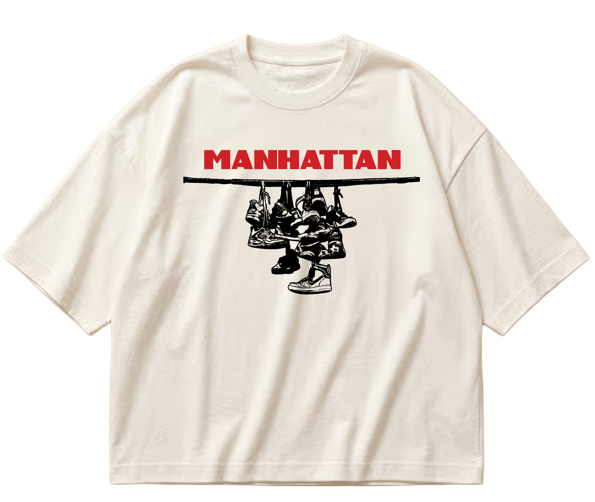 Off-white boxy cropped Sneaker Hang tee with red Manhattan lettering above a black hanging-sneakers design